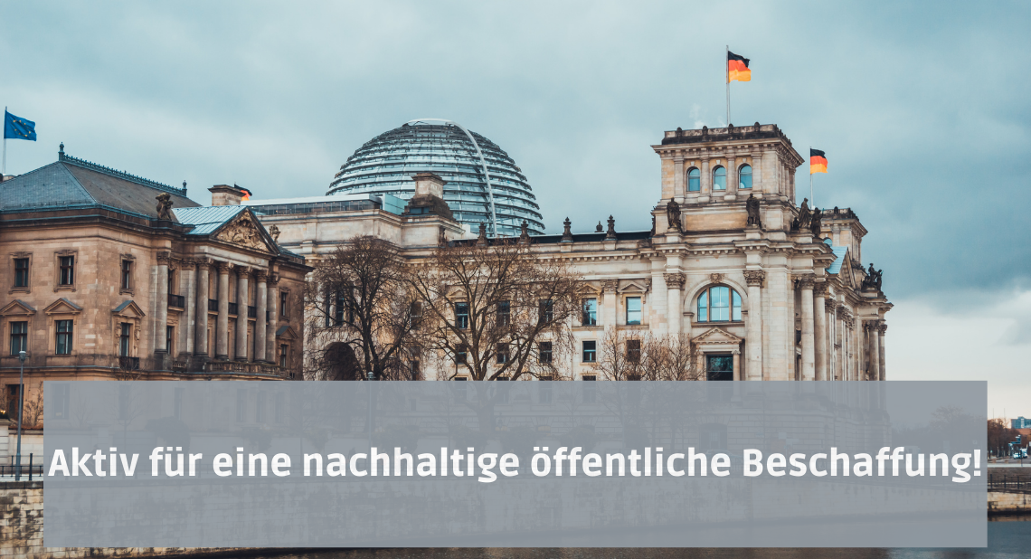 Der Schriftzug "Aktiv für eine nachhaltige öffentliche Beschaffung!" vor dem Reichstaggebäude, welches heute als Deutscher Bundestag fungiert. Das Gebäude ist mit Deutschland-, sowie mit einer EU-Flagge bestückt