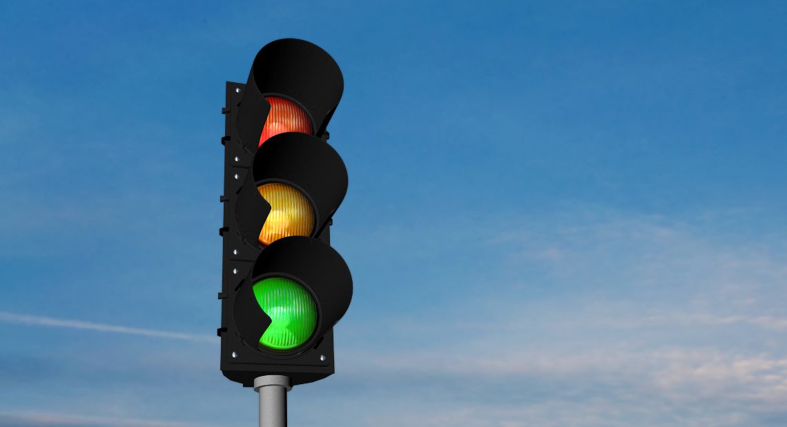 Eine Ampel in der alle Lichter leuchten vor blauem Himmel