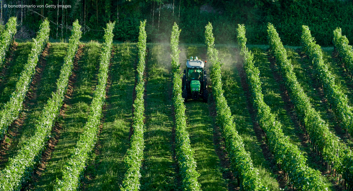 Bild von Traktor auf Feld, der Pestizide versprüht.