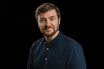 Porträt von Sebastian Sladek vor schwarzem Hintergrund