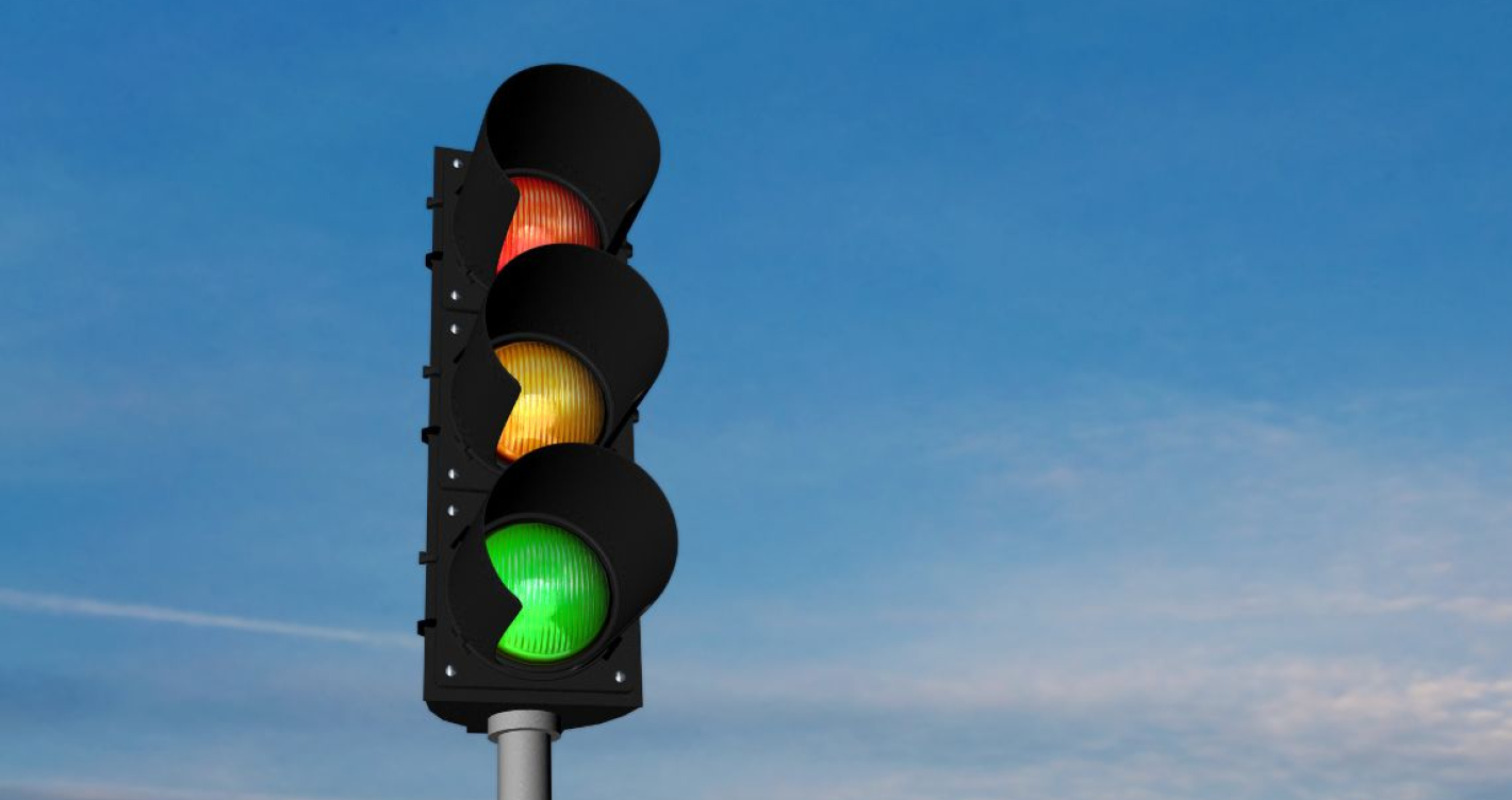 Eine Ampel in der alle Lichter leuchten vor blauem Himmel