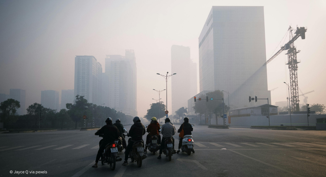 Scooter vor Hochhäusern auf einer Straße im Smog