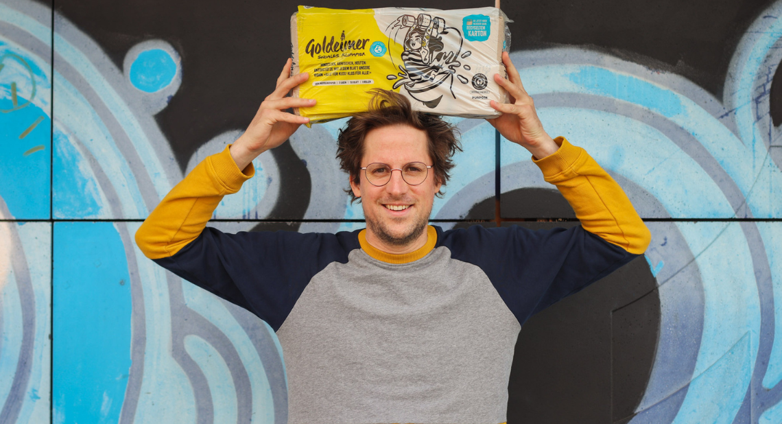 Malte Schremmer, Gründer von Goldeimer, mit Goldeimer Klopapier in den Händen