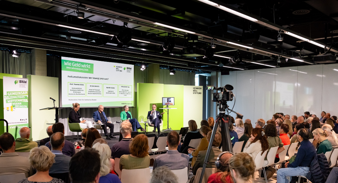 Vier Diskutierende auf der Bühne bei der BNW-Jahrestagung 2026 „Wie Geld wirkt“, das Publikum hört zu