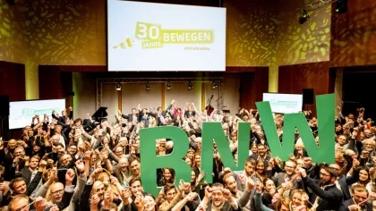 Teilnehmende der Jubiläumsveranstaltung halten die Buchstaben BNW in die Luft