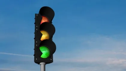 Eine Ampel in der alle Lichter leuchten vor blauem Himmel