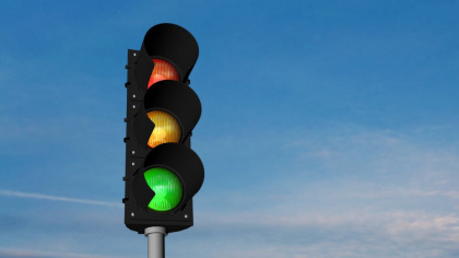 Eine Ampel in der alle Lichter leuchten vor blauem Himmel