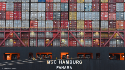 Containerschiff von hinten aufgenommen mit Containern auf Deck