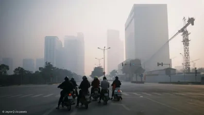 Scooter vor Hochhäusern auf einer Straße im Smog